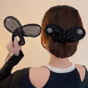 A woman with her back to the camera models a black mesh rabbit ear headband featuring white polka dots and sparkling silver circular embellishments. She holds a second, similar headband in her hand.